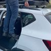 Autoportier opstapje in gebruik bij dakkoffer Persoon gebruikt autoportier opstapje om dakkoffer te bereiken