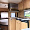 Keukenblok met kookplaat en zicht op vast bed in caravan