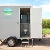 Ingang van de mobiele badkamer Geopende ingang van mobiele badkamer met opstap en toilet zichtbaar
