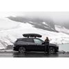 Auto met Thule dakkoffer in bergachtig en besneeuwd landschap tijdens reis