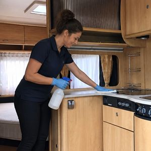 Eindschoonmaak caravan binnen door professionele schoonmaak Schoonmaakster maakt de binnenkant van een caravan schoon tijdens eindschoonmaak