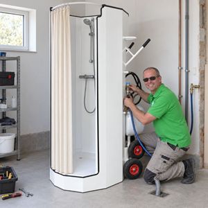 Professionele installatie van een mobiele douche Monteur van Campin sluit een mobiele douche met boiler en waterpompen aan in een garage