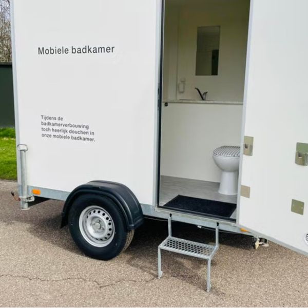 Mobiele badkamer met toilet op aanhanger Mobiele badkamer aanhanger met toilet en wastafel zichtbaar via open deur