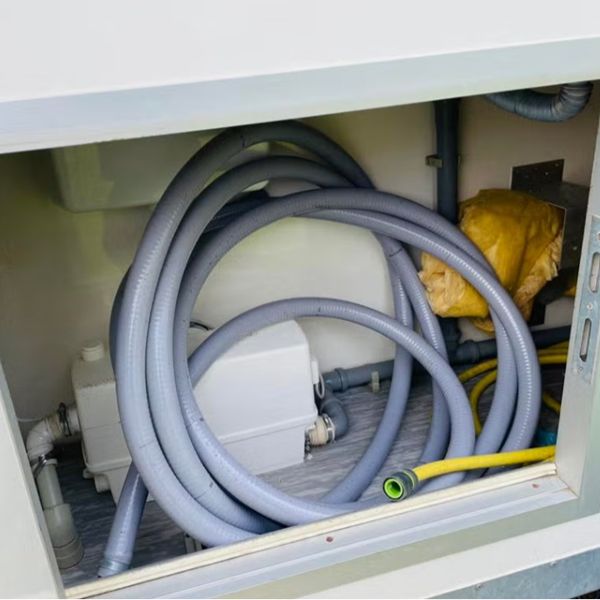 Mobiele badkamer technische ruimte en aansluitingen Technische ruimte van mobiele badkamer met slangen en aansluitingen