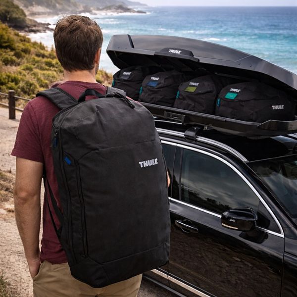 Thule dakkoffer met tassenset op auto – perfect voor vakantie aan zee Thule dakkoffer met reistassen op auto bij kust en zee