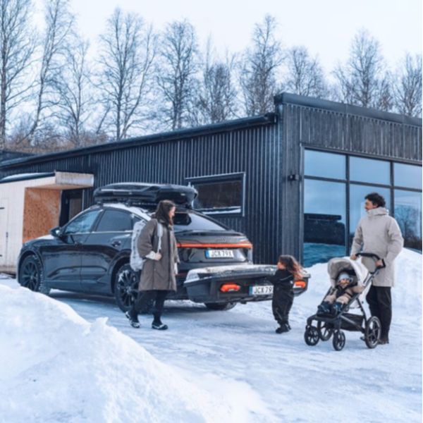 Trekhaakkoffer eenvoudig laden en lossen Persoon plaatst ski’s in een open trekhaakkoffer achter op de auto